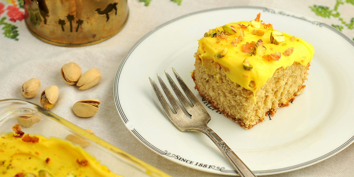 بعد از پخت دسر با استفاده از طرز تهیه کیک زعفرانی بدون شیر آن را با گل و مغزی جات تزئین کنید.